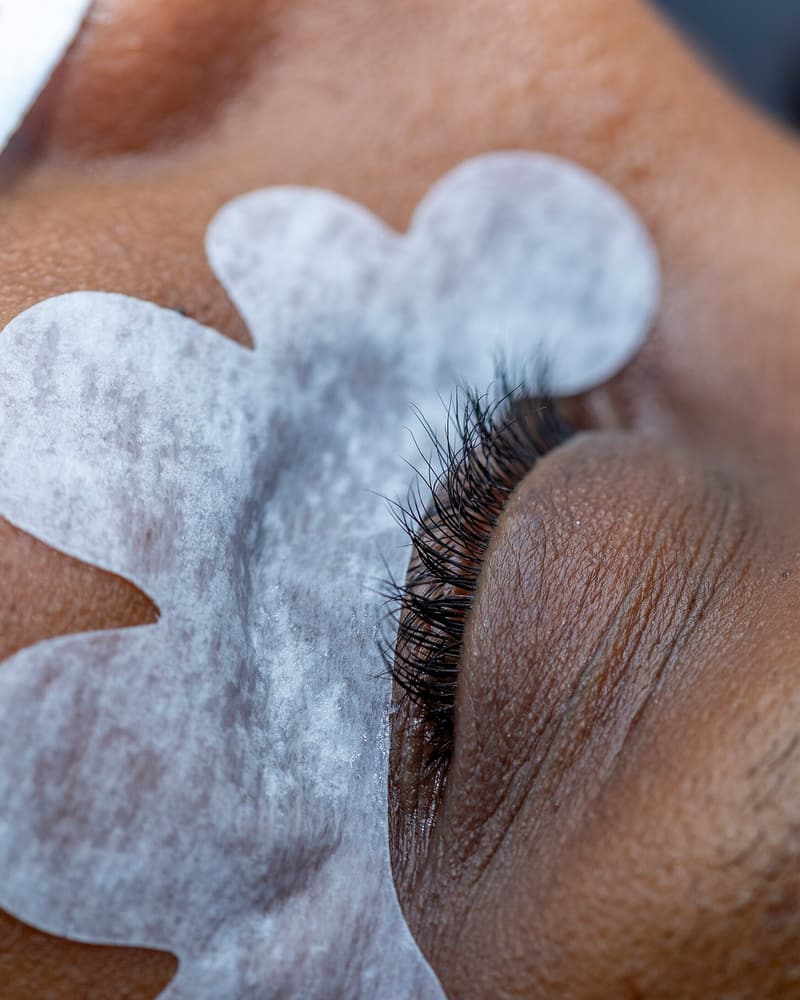 Close-up of lash extensions being applied with under-eye pads